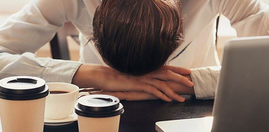 man with his head down at a desk